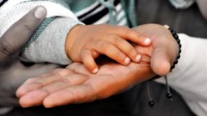 small child's hand on parents hand