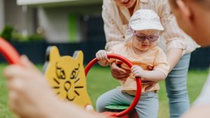 adult holding child on playground equipment